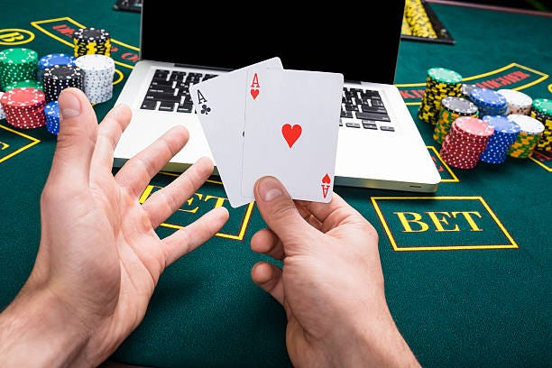 Close up a man holding cards in front of laptop